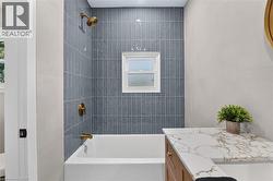 Tub and shower combination with vertical tile surround and brass fixtures -
