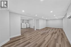 Spacious room featuring wood-finish flooring, recessed lighting, and light-toned wall finishes -