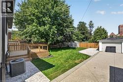 Expansive backyard featuring a multi-level wood deck, manicured lawn, concrete patio, and detached garage -