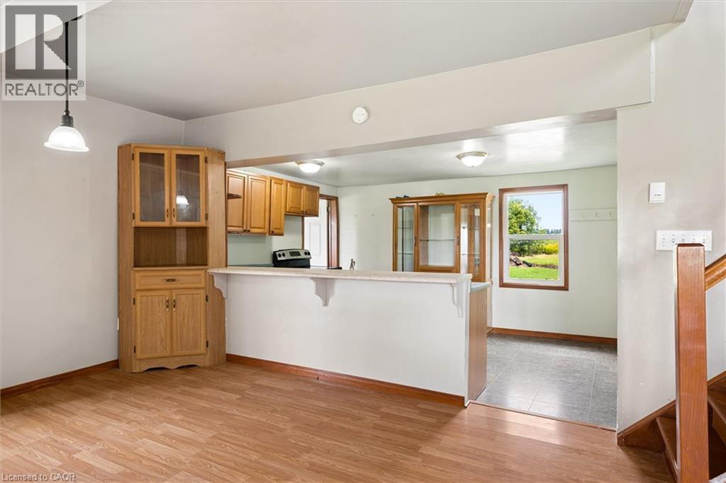 Wood-finish flooring, built-in corner cabinet with glass-front uppers, and a kitchen pass-through with a breakfast bar - 5480 Line 42 Line, Mitchell, ON