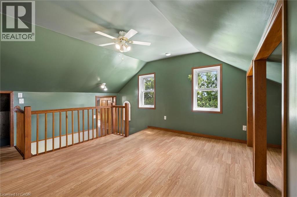 Sloped ceilings, wood-finish flooring, two windows, wood railing, and a ceiling fan with integrated lighting - 5480 Line 42 Line, Mitchell, ON