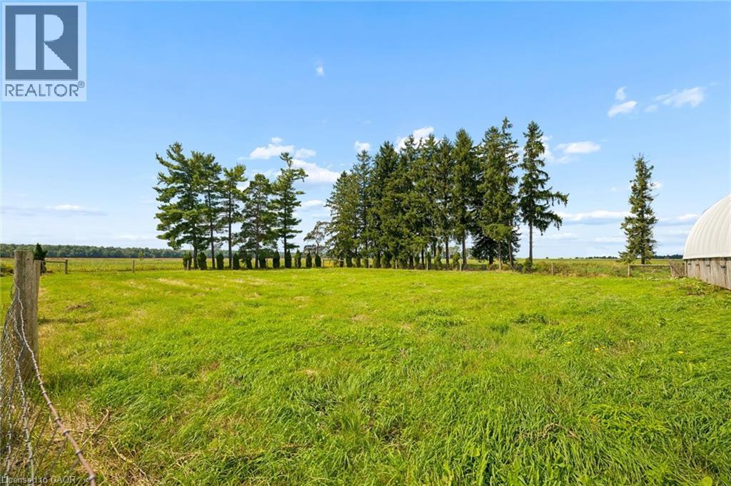 Expansive green field with mature trees and a partial barn structure - 5480 Line 42 Line, Mitchell, ON
