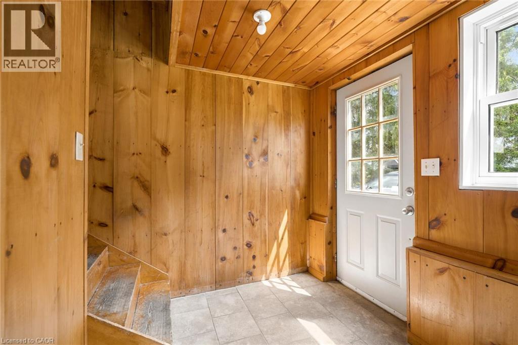 Wood-paneled room featuring a white paneled door with windowpanes, a square window, and light-toned floor tiles - 5480 Line 42 Line, Mitchell, ON