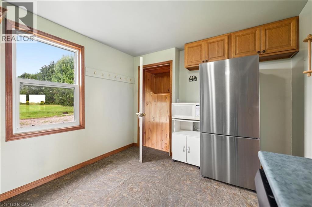 Stainless steel refrigerator, wood-finish cabinetry, and a window with wood-finish trim - 5480 Line 42 Line, Mitchell, ON