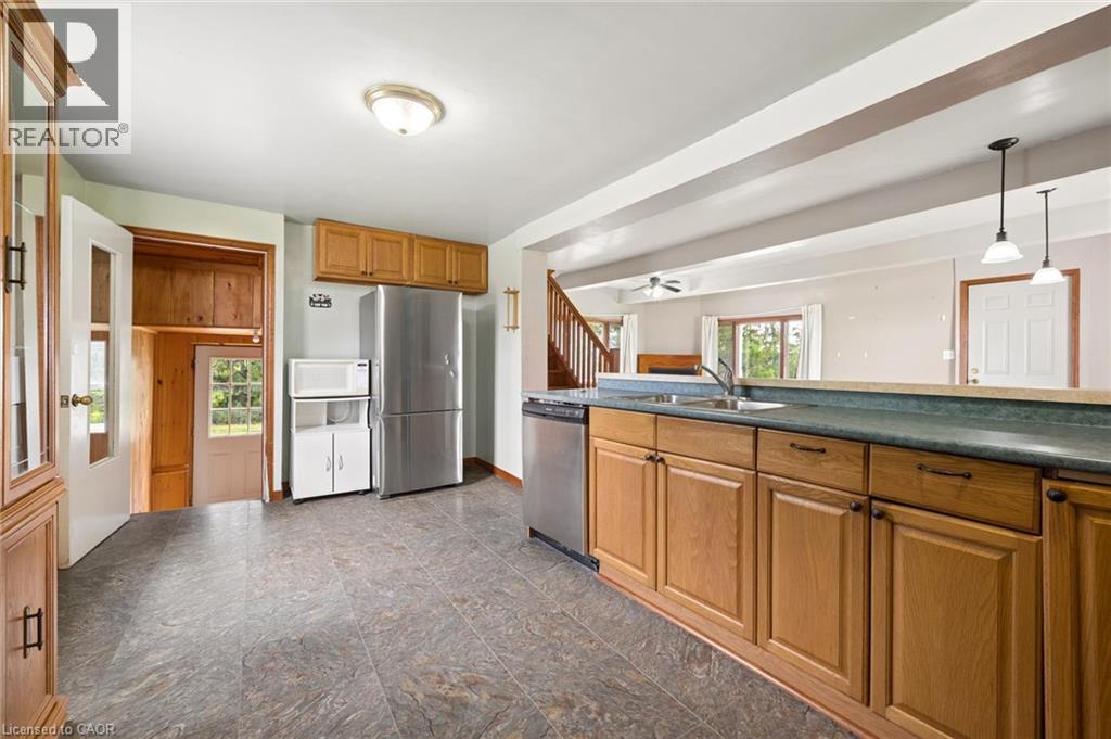 Spacious kitchen featuring wood cabinetry, stainless steel appliances, slate-finish flooring, and a generous island with seating - 5480 Line 42 Line, Mitchell, ON