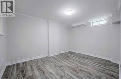 Light gray walls, wood-finish flooring, white crown molding, white baseboards, and a flush mount ceiling light - 