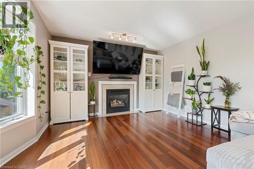 Hardwood flooring, fireplace with stone surround, track lighting, built-in display cabinetry, and a large window - 260 Granite Hill Road, Cambridge, ON 