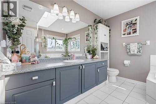 Double vanity with gray cabinetry and white countertop, white tiled flooring, and a skylight - 260 Granite Hill Road, Cambridge, ON 