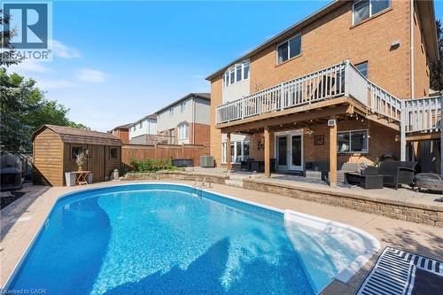 In-ground swimming pool with surrounding patio, elevated wood deck with white railings, and a detached wood shed - 260 Granite Hill Road, Cambridge, ON 