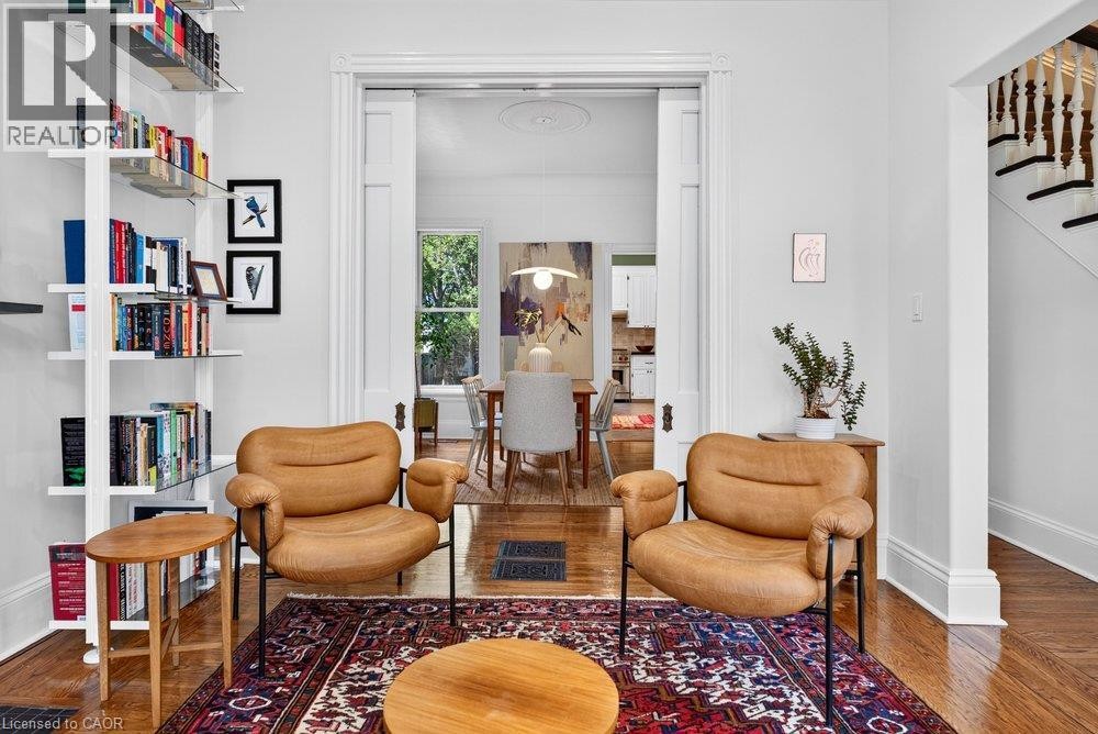 Hardwood flooring throughout, white built-in shelving, traditional baluster staircase, and a doorway with pocket doors - 16 Bruce Street, Hamilton, ON