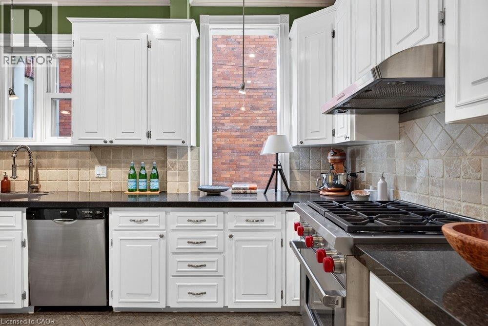 White cabinetry with dark countertops, stainless steel appliances, and a tiled backsplash - 16 Bruce Street, Hamilton, ON