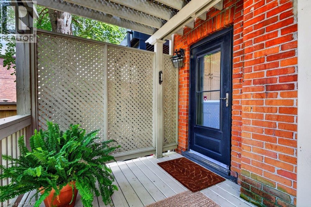 Wood deck with privacy lattice, brick exterior, and dark-framed glass paneled door - 16 Bruce Street, Hamilton, ON