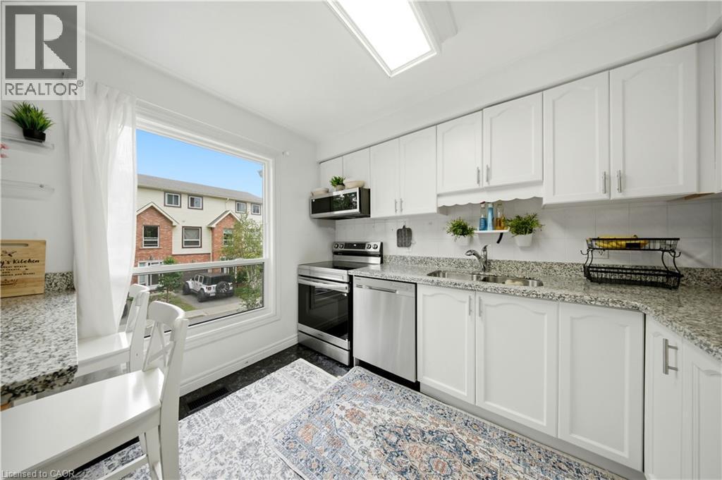 White kitchen cabinetry with stainless steel appliances, granite-style countertops, and a tile backsplash - 384 Limeridge Road E Unit# 16, Hamilton, ON