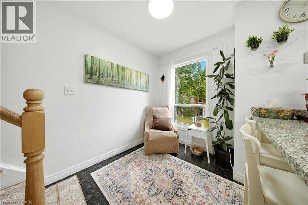 Hardwood-finish staircase with turned newel post, large window, dark tile flooring, and light-toned walls - 384 Limeridge Road E Unit# 16, Hamilton, ON