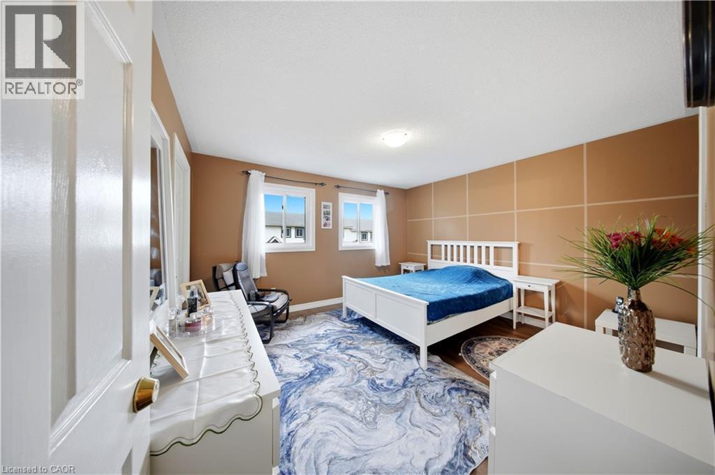 Bright room with two windows, light wood-finish flooring, and a decorative accent wall - 384 Limeridge Road E Unit# 16, Hamilton, ON