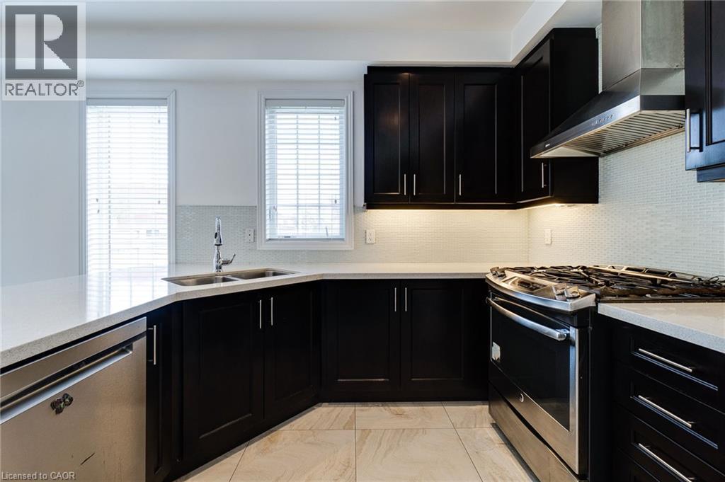 Kitchen featuring dark wood cabinetry, light-toned countertops, stainless steel appliances, and a tiled backsplash - 2 Hawstone Road, Vellore, ON
