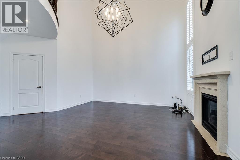 Wood-finish flooring, high ceilings, contemporary chandelier, stone fireplace surround, and plantation shutters - 2 Hawstone Road, Vellore, ON