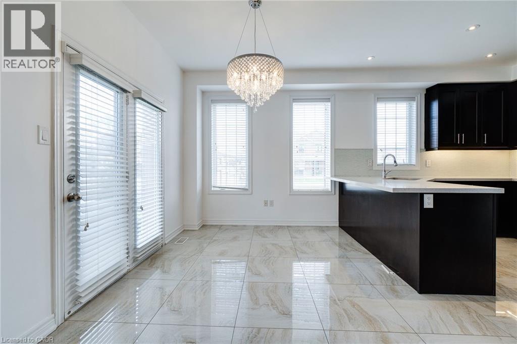 Kitchen area with an island featuring a built-in sink, dark cabinetry, and light countertops - 2 Hawstone Road, Vellore, ON