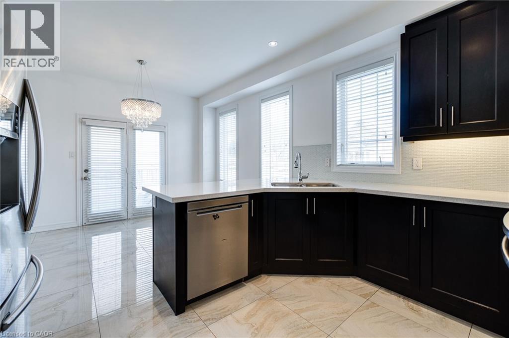 Modern kitchen featuring dark cabinetry, light countertops, a stainless steel dishwasher, and a tile backsplash - 2 Hawstone Road, Vellore, ON