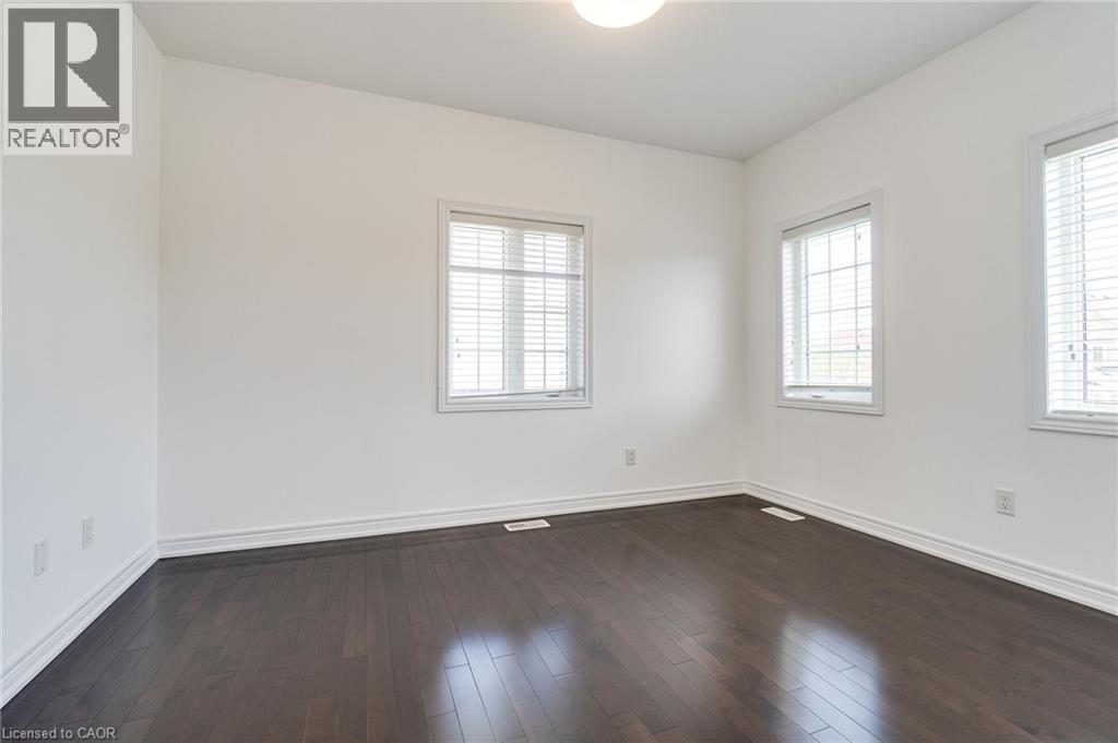 Rich wood-finish flooring, multiple windows with blinds, and a flush mount ceiling light - 2 Hawstone Road, Vellore, ON