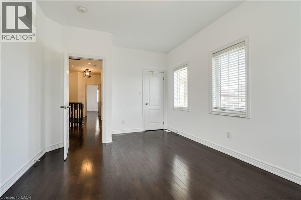 Dark wood-finish flooring, white walls, two windows with horizontal blinds, and white trim - 2 Hawstone Road, Vellore, ON