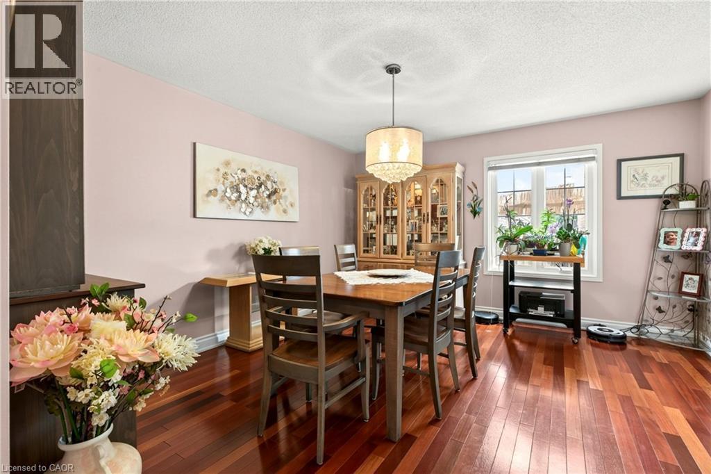 Wood-finish flooring, overhead chandelier, large window with white trim, light-toned wall color, built-in display cabinetry - 31 Grindstone Way, Hamilton, ON