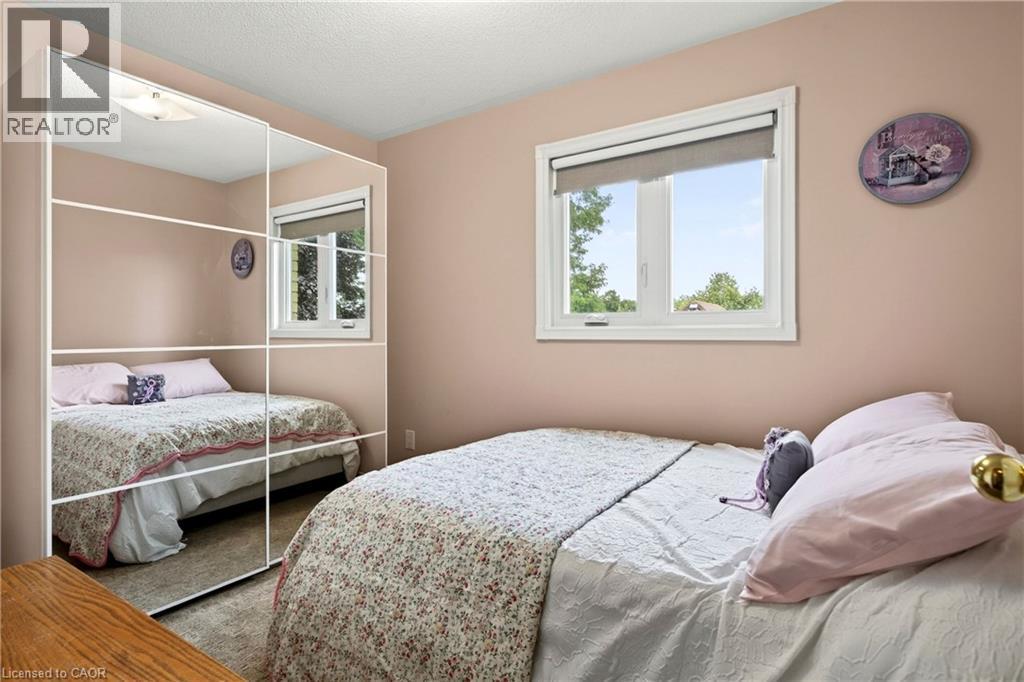 Mirrored wardrobe with multiple panels, large window with roller shade, and ceiling-mounted light fixture - 31 Grindstone Way, Hamilton, ON