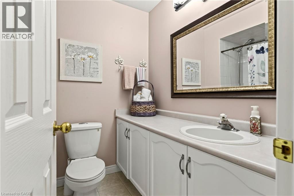 Vanity with integrated sink, white cabinet storage, and an ornate framed mirror - 31 Grindstone Way, Hamilton, ON
