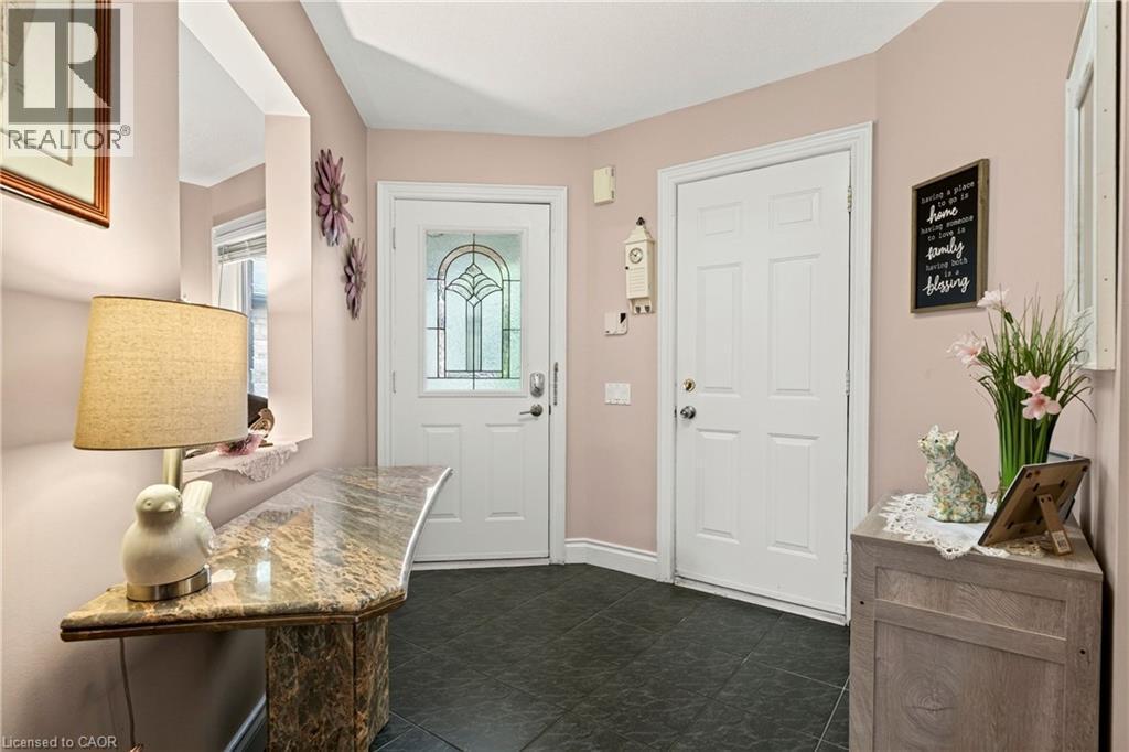 Entryway featuring dark-toned floor tiles, a console table with a polished stone surface, and two white panel doors - 31 Grindstone Way, Hamilton, ON