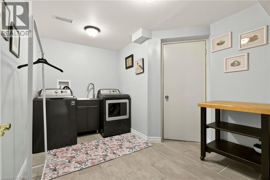 Laundry area featuring tile flooring, built-in cabinetry with a sink, and a flush-mount ceiling light - 31 Grindstone Way, Hamilton, ON
