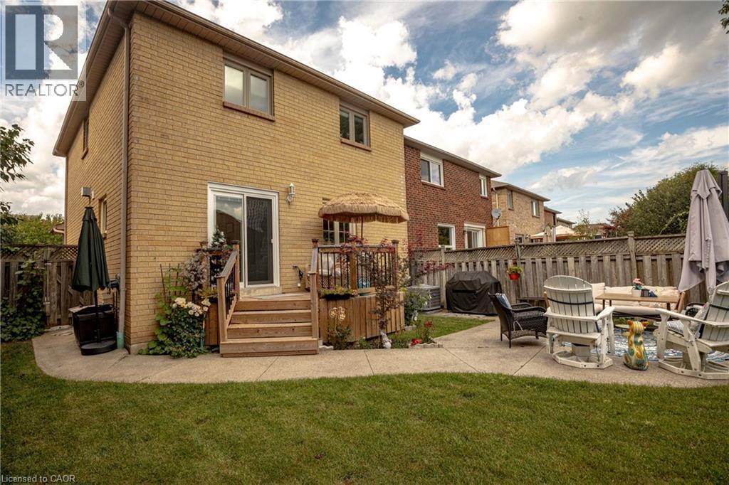 Expansive backyard featuring a manicured lawn, concrete patio, and wood privacy fencing - 31 Grindstone Way, Hamilton, ON