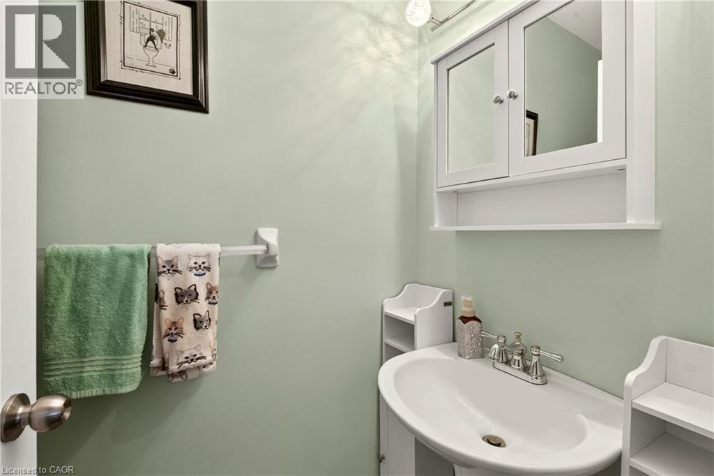 Pedestal sink with chrome-finish faucet, medicine cabinet with mirrored doors, and overhead lighting - 31 Grindstone Way, Hamilton, ON