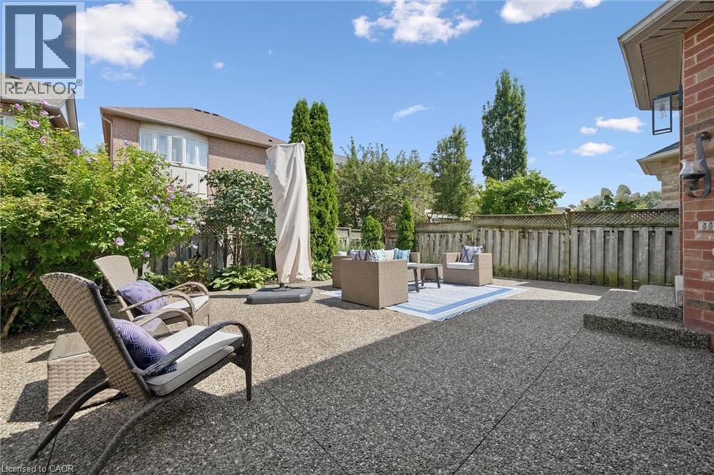 Expansive patio with exposed aggregate surface, mature perimeter landscaping, and a privacy fence - 2294 Seton Crescent, Burlington, ON