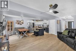 Open-concept living space featuring wood-finish flooring, a modern ceiling fan, and recessed lighting - 