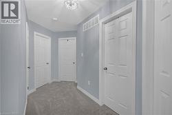 Hallway featuring light blue walls, gray carpet, white trim, and a contemporary ceiling light fixture - 