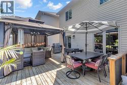 Expansive outdoor deck featuring a gazebo, sliding glass door access, and an exterior wall light fixture - 