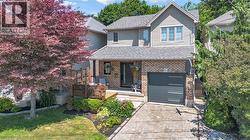 Two-story residence featuring a brick and siding exterior, front deck, paver driveway, and an attached garage - 