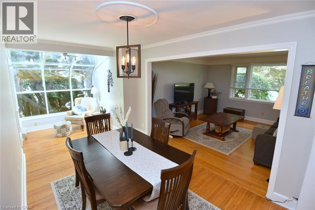 Wood-finish flooring throughout, recessed lighting, crown molding, open archway, and a sunroom with expansive windows - 936 Boothman Avenue, Burlington, ON