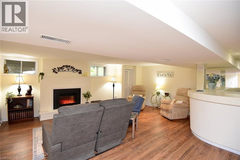 Recessed ceiling, wood-finish flooring, built-in electric fireplace, curved built-in bar, and multiple windows - 936 Boothman Avenue, Burlington, ON
