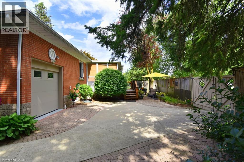 Brick exterior featuring an integrated garage, concrete driveway, and paver stone accents - 936 Boothman Avenue, Burlington, ON