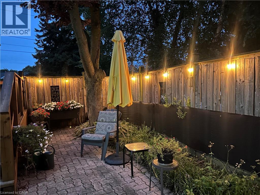 Paver patio with a wood privacy fence, string lighting, and integrated plantings - 936 Boothman Avenue, Burlington, ON