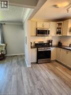 Modern kitchen featuring cream cabinetry with glass-front upper doors, stainless steel appliances including a five-burner cooktop and built-in microwave, subway tile backsplash, and black countertops - 