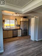 Kitchen featuring wood-finish flooring, stainless steel appliances, track lighting, and a window with a sink - 