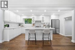 Kitchen featuring white shaker cabinetry, stainless steel appliances, a white subway tile backsplash, and wood-finish flooring - 