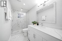 White vanity with an integrated sink and chrome faucet, full-width framed mirror with overhead lighting, glass-enclosed shower with a window, wall-mounted shower fixtures, and marble-look flooring - 