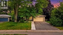 Charming single-story residence featuring a freshly paved driveway, mature landscaping with established trees throughout the property, and a spacious lawn - 