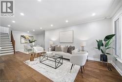 Bright, open-concept living area featuring hardwood flooring throughout, recessed ceiling lighting, and large windows with natural light - 