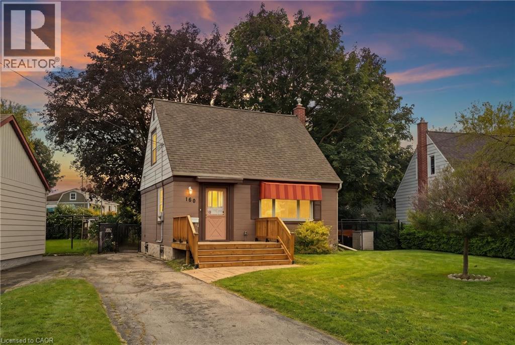 Front facade featuring a sloped roofline, wood deck, and red window awning - 160 Lorne Crescent, Kitchener, ON