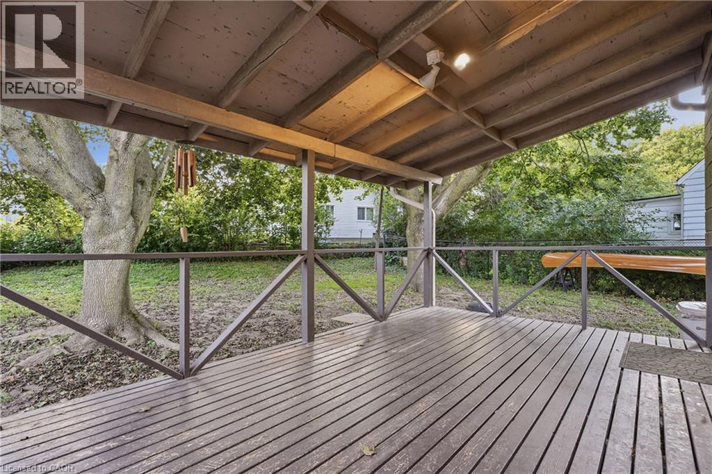 Covered wood deck with wooden railings, exposed wood beam ceiling, and overhead lighting - 160 Lorne Crescent, Kitchener, ON