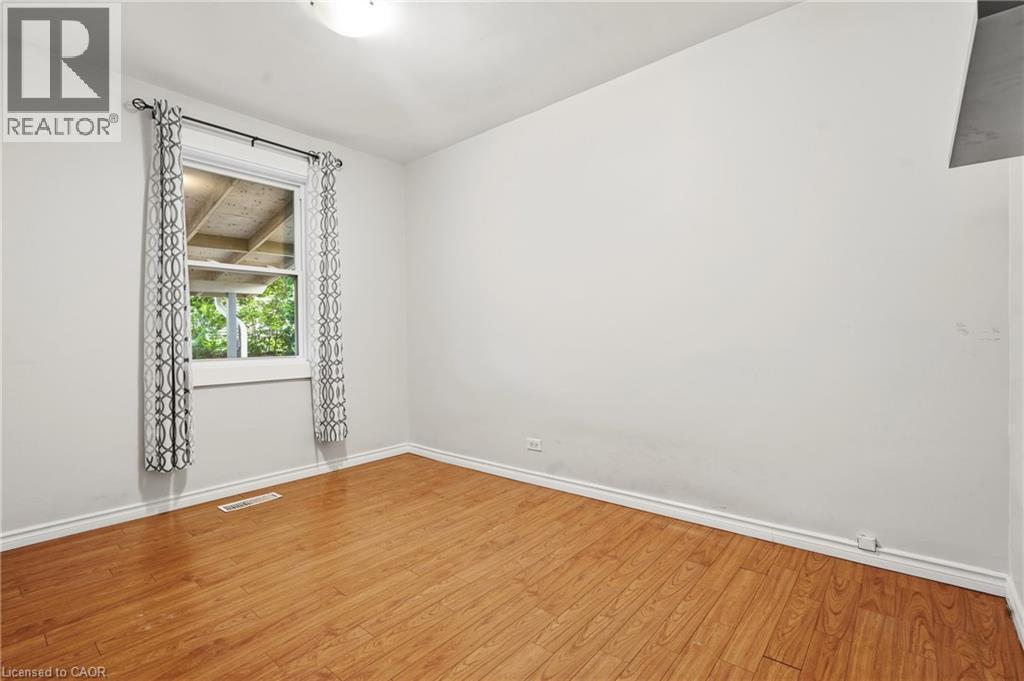 Wood-finish flooring with white trim, featuring a single window with a white frame - 160 Lorne Crescent, Kitchener, ON